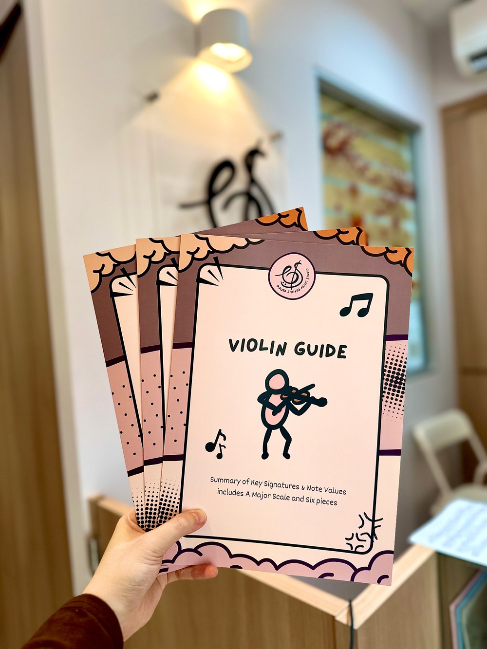 The Bowed Strings Violin Guide booklets held up at the studio